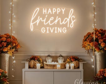 May include: A wall-mounted neon sign featuring the text HAPPY friends GIVING in a warm white glow. The word HAPPY and GIVING are in a clean sans-serif font, while the word friends is in a flowing, cursive script, all enclosed in a soft outline.