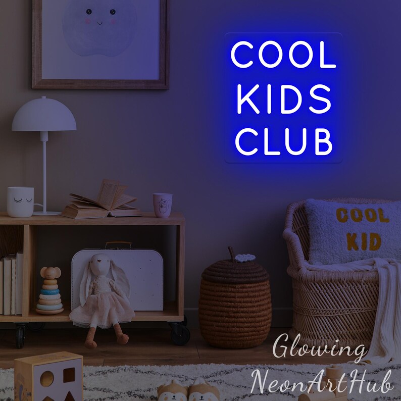 May include: A neon sign in blue, displaying the text "COOL KIDS CLUB" in white. The sign is in a child's room, with a wooden shelf, toys, and a woven basket. The room has a neutral colour scheme.