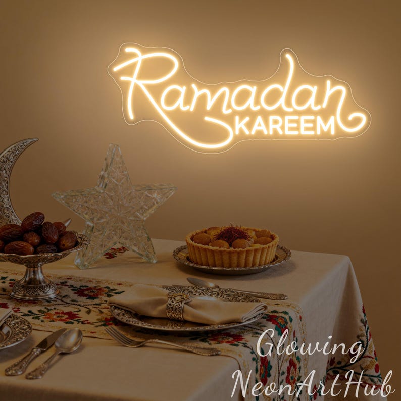 May include: A warm-toned image features a neon sign that reads "Ramadan Kareem." A table is set with a decorative tablecloth, silverware, and a tart. Other decorations include a crescent moon, a star, and a bowl of dates.