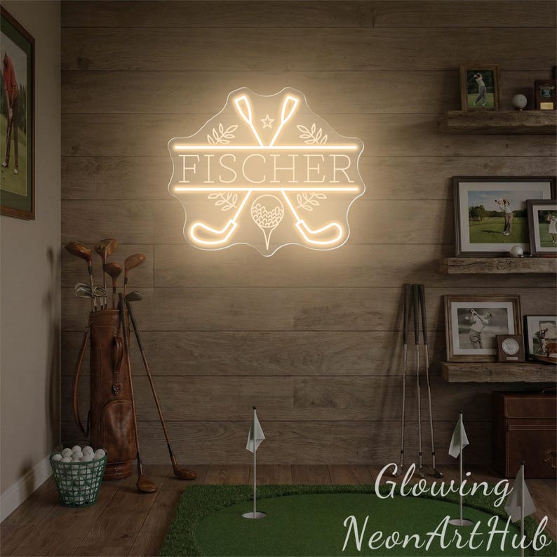 Puede incluir: Un letrero de ne&oacute;n con el nombre "FISCHER" en un marco decorativo, con palos de golf y una pelota de golf. El letrero se ilumina en un color blanco c&aacute;lido y est&aacute; montado en una pared de madera. Tambi&eacute;n se ven palos de golf y una bolsa de golf.