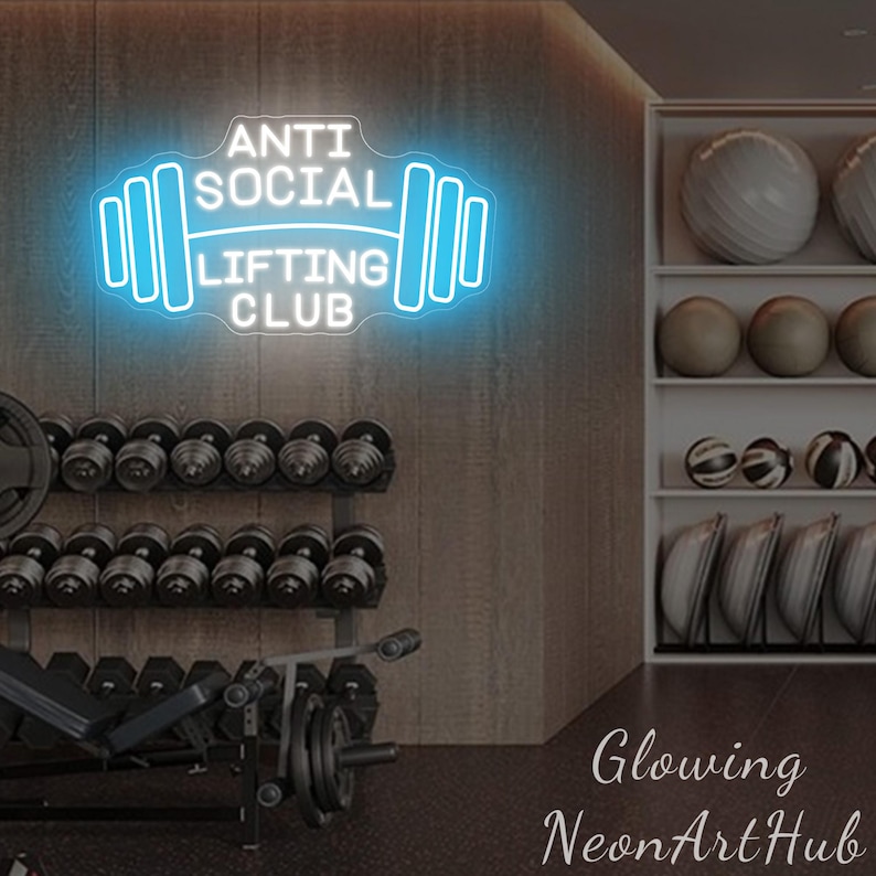 Pu&ograve; includere: Un'insegna al neon in palestra con la scritta "ANTI SOCIAL LIFTING CLUB" in bianco e azzurro, a forma di bilanciere. Sullo sfondo si vedono manubri, rastrelliere per pesi, palle da ginnastica e dischi.