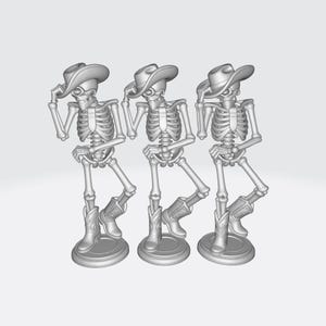 May include: Three gray skeleton figurines wearing cowboy hats and boots. Each skeleton is posed in a different stance, with one hand on their hat. The figures are standing on round bases.