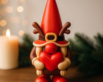 Puede incluir: Figura de gnomo festivo con gorro puntiagudo rojo y cuernos de reno. El gnomo sostiene un corazón rojo y lleva un cinturón marrón con hebilla dorada. La figura está sobre una superficie de madera.