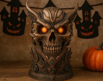May include: A detailed, brown skull-shaped Halloween decoration with glowing orange eyes and intricate carvings. The skull has horns and is decorated with teal accents. A pumpkin and Halloween-themed decorations are in the background.