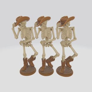 May include: Three skeleton figurines wearing cowboy hats and boots. The skeletons are posed in a dancing stance, with one leg raised. The hats are brown, and the boots are a darker brown. Each figurine stands on a circular base.