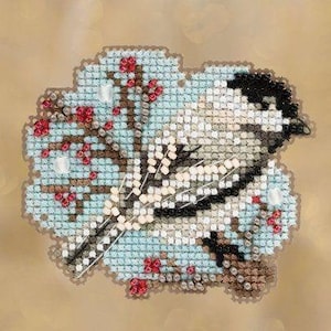 Könnte beinhalten: Eine Kreuzstichstickerei mit einem Vogel mit schwarzem Kopf und weißem Körper, der auf einem braunen Ast sitzt. Das Design umfasst hellblaue Hintergrundstiche, rote Beerenakzente und weiße Perlen, die in die Stoffstruktur eingearbeitet sind.