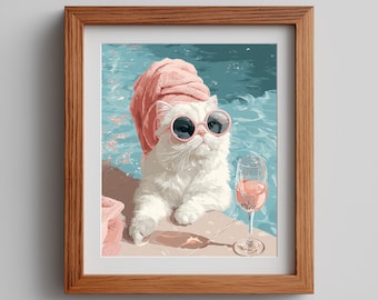 Op de afbeelding: Een ingelijste print van een witte kat met een roze zonnebril en handdoek bij een zwembad. Een glas rosé staat ernaast. Het kunstwerk heeft een grillige, zomerse sfeer met blauw water.