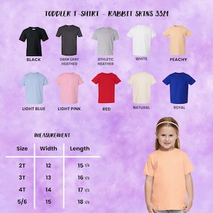 Op de afbeelding: Een verscheidenheid aan peuter-T-shirts in verschillende kleuren, waaronder zwart, grijs, wit en blauw. De afbeelding bevat een maattabel met afmetingen in inches. De tekst bovenaan luidt "TODDLER T-SHIRT - RABBIT SKINS 3321".