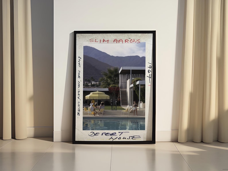 May include: Framed print of a Slim Aarons photograph titled "Desert House" from 1967. The image depicts a mid-century modern home with a pool, mountains in the background, and people relaxing. The text "Shot for Holiday Cover" is also visible.