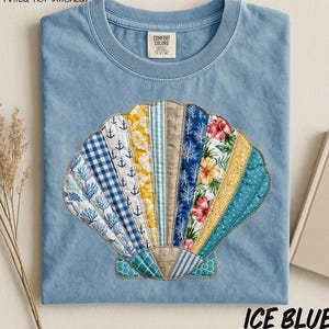 May include: Ice blue t-shirt featuring a colorful seashell design. The seashell is made of various patterned fabrics, including floral, anchor, and striped patterns. The text "Faux Patchwork Design (Printed not stitched)" is above the design, and "ICE BLUE" is below.