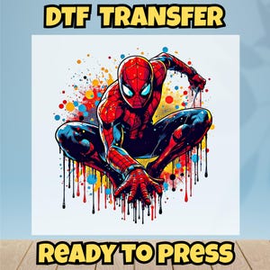 May include: A DTF transfer featuring a dynamic illustration of Spider-Man in a crouching pose, rendered in vibrant red, blue, and black. The image includes colorful paint splatter effects and the text "DTF TRANSFER" and "READY TO PRESS".