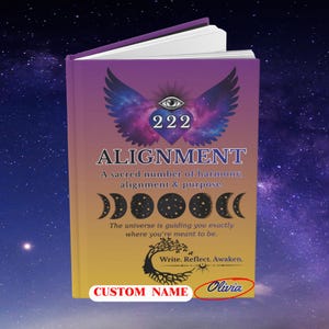 May include: A hardcover book with a purple and yellow gradient cover. The cover features a heart with wings, an eye, and the number 222. The word "ALIGNMENT" is displayed in large letters. The book includes the name "Olivia" and the words "CUSTOM NAME".