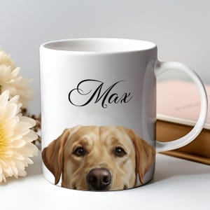 Puede incluir: Taza de cerámica blanca con la cara de un Labrador Retriever. El nombre "Max" está escrito en negro sobre la cabeza del perro. La taza tiene un asa curva. El perro tiene ojos marrones y nariz marrón.