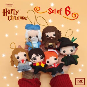 Peut inclure: Un ensemble de six ornements de Noël en feutre représentant des personnages d'une série fantastique populaire. Chaque ornement est un personnage différent, avec des détails tels que des lunettes, des écharpes et des chapeaux. Les ornements sont tenus dans les mains d'une personne sur un fond orange clair.