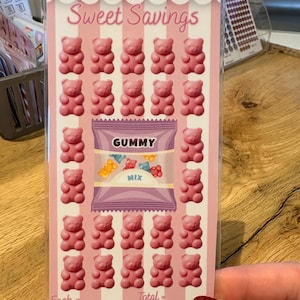 May include: A pink and white card featuring the text "Sweet Savings" and rows of pink gummy bear illustrations. A purple bag of "Gummy Mix" is in the center. The card also includes the text "Each =" and "Total =."