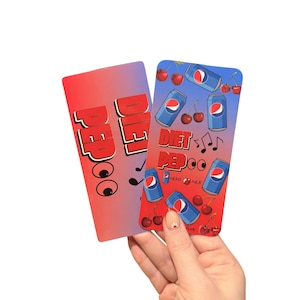 May include: Two rectangular cards with a Diet Pepsi theme. One card has the words "Diet Pepsi" in white, with eyes and musical notes. The other card has blue Diet Pepsi cans, cherries, and the words "Diet Pepsi".