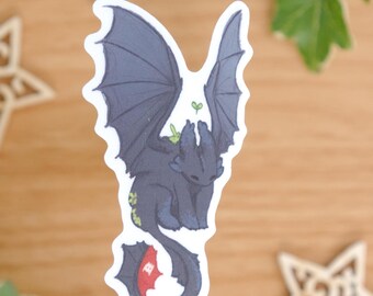 May include: A die-cut sticker featuring a dark blue dragon with large wings, small green sprouts on its back, and a tail ending in a red and black fin. The dragon is depicted in a seated position with its head bowed. The text reads by mossyleaf studio.