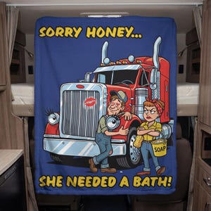 May include: A blue blanket featuring a cartoon illustration of a red lorry with eyelashes, a man with heart-shaped eyes, and a woman holding a bucket of soap. Text reads "SORRY HONEY... SHE NEEDED A BATH!"