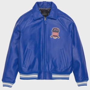 May include: A vibrant blue leather jacket with a classic bomber style. Features a ribbed collar, cuffs, and hem with white stripes. Includes a front zipper and a patch with an American flag design. The jacket has two front pockets.