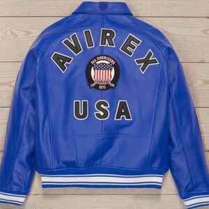 May include: A royal blue leather jacket with the word "AVIREX" arched across the shoulders in white lettering with black outlines. Below the word "AVIREX" is a circular patch with the words "ALL AMERICANS ESTABLISHED 1975" and a US flag design. The word "USA" is below the patch.