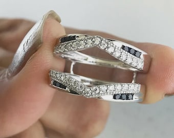 May include: Two silver rings with a twisted design. One ring is adorned with small white stones and black stones. The rings are held up by a person's fingers.