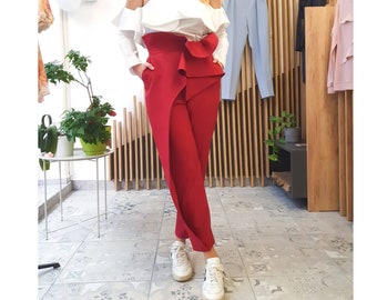 Red TROUSERS with a high rise and asymmetrical flounces at the waist