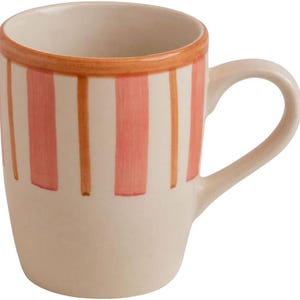 May include: A cream-coloured ceramic mug with vertical coral and orange stripes. The mug has a rounded handle and an orange band around the rim. The design is simple and the mug appears to be handmade.