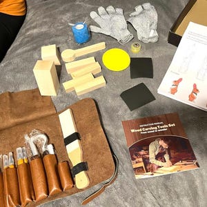 May include: A wood carving tools set with various tools in a brown leather roll, wooden blocks, gloves, sandpaper, and a template with rabbit illustrations. The instruction manual is visible.