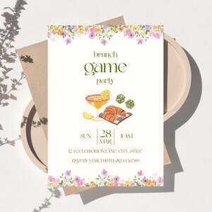 May include: An invitation for a brunch game party, decorated with floral elements. The design includes a margarita, dice, and a croissant. The text provides the date, time, and RSVP details. The overall aesthetic is light and elegant.