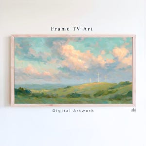 May include: A framed landscape painting with a light wood frame. The artwork depicts a serene scene of three white crosses on a green hill under a sky filled with pastel-colored clouds. The text "Frame TV Art" and "Digital Artwork" are visible.