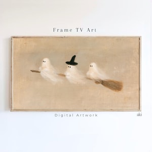 以下が含まれることがあります： Frame TV Artと題された長方形のデジタルアート作品。質感のあるベージュの背景に、茶色のほうきに乗って飛ぶ3体の白い幽霊が描かれています。中央の幽霊は小さな黒いとんがり帽子をかぶっています。下にDigital Artworkという文字があります。