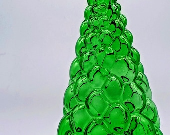 May include: A vibrant green glass bottle with a textured, bubble-like surface pattern that tapers towards a narrow neck. Beside the bottle sits a clear glass stopper featuring a small, rounded top and a tapered, frosted glass plug base.