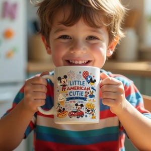 K&ouml;nnte beinhalten: Ein l&auml;chelndes Kind h&auml;lt einen wei&szlig;en Becher mit Cartoon-Figuren und Feuerwerk. Auf dem Becher steht der Text "Little American Cutie 1776-2026". Das Kind tr&auml;gt ein gestreiftes Oberteil.