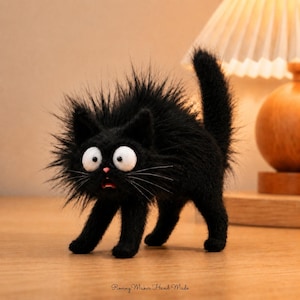 Könnte beinhalten: Eine schwarze Katzenfigur mit langem, stacheligem Fell, großen weißen Augen, einer kleinen rosa Nase und einem geöffneten Mund, der Rot zeigt. Die Katze steht in einer gebogenen Haltung mit erhobenem Schwanz. Der Text Roving Maker Hand Made steht unten.
