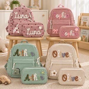 May include: Four corduroy backpacks and matching pencil cases in pink, green, and beige. Each item is personalized with names like Luna, Sophia, Arthur, and Oliver in raised fabric lettering, featuring decorative patches like flowers, bunnies, and dinosaurs.