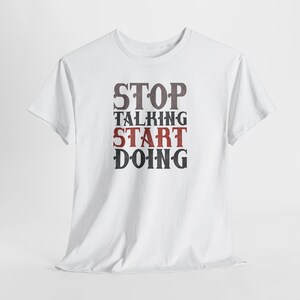May include: White t-shirt featuring the text "STOP TALKING START DOING" in a distressed font. The words are in grey and red. The shirt has a crew neck and short sleeves.