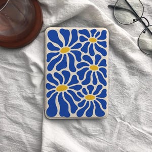 May include: A rectangular phone case with a repeating floral pattern. The design features large blue flowers with yellow centres on a cream background. The case is a modern accessory with a retro aesthetic.