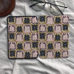 Puede incluir: Una funda para lector electr&oacute;nico con un patr&oacute;n de tablero de ajedrez repetitivo de flores azul marino oscuro sobre un fondo rosa claro y flores rosa claro sobre un fondo verde oliva. La funda est&aacute; abierta, mostrando el dise&ntilde;o interior y unas gafas.