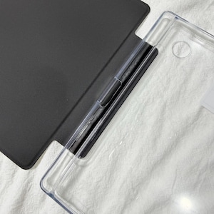 Puede incluir: Una funda protectora para tableta que presenta una cubierta negra mate unida a una carcasa trasera transparente. El dise&ntilde;o incluye una secci&oacute;n de bisagra negra dedicada para el soporte del dispositivo, con una construcci&oacute;n funcional.