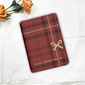 May include: Rectangular red plaid pattern item with a beige bow graphic and the text "For you a thousand times over." The item has a dark red, beige, and brown plaid design.