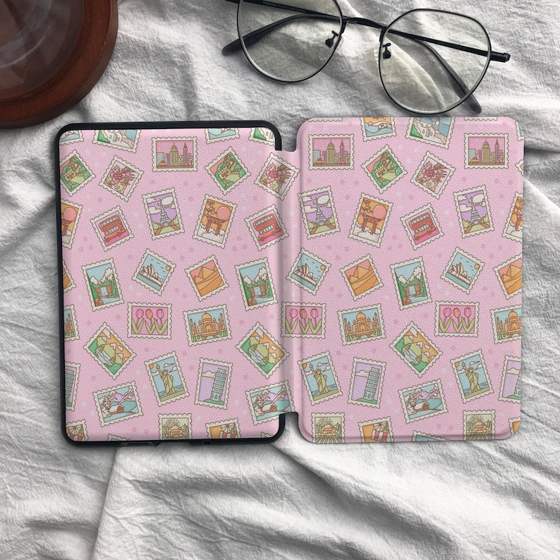 May include: A protective e-reader cover featuring a repeating pattern of colorful postage stamps depicting global landmarks on a light pink background. The design includes illustrations of the Eiffel Tower, the Statue of Liberty, and tulips.