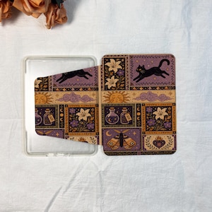 May include: A rectangular clear plastic case featuring a decorative cover with a repeating grid pattern. The design includes illustrations of a black cat, lilies, potion bottles, a sun, clouds, a moth, and a flaming heart in purple and gold.