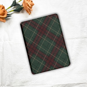 May include: A rectangular, green and burgundy plaid pattern. The pattern features intersecting lines in a grid-like design. The plaid is a classic design, with a dark green base and burgundy and gold intersecting lines. The item is likely a decorative mat or pad.