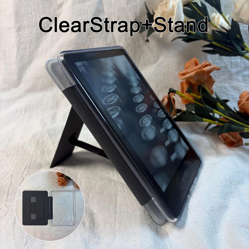 May include: A clear protective case for an e-reader featuring an integrated black kickstand and a hand strap on the back. The case is shown attached to a device, with an inset image displaying the open case structure and the text ClearStrap+Stand.