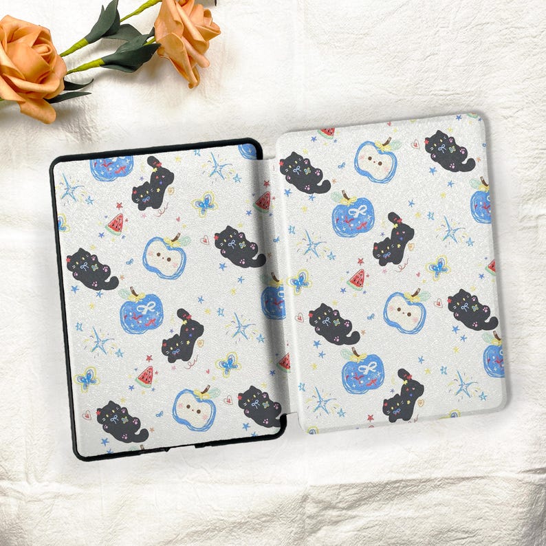 Pode incluir: Duas capas brancas para tablet com um padr&atilde;o repetido de silhuetas de gatos pretos, ma&ccedil;&atilde;s azuis, fatias de melancia, borboletas e estrelas. As capas est&atilde;o abertas, revelando o interior.