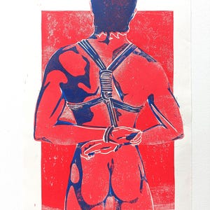 Pu&ograve; includere: Una stampa rossa e blu di una persona vista da dietro, con un'imbracatura e le mani legate dietro la schiena. La stampa ha un aspetto strutturato, con la figura in rosso su sfondo rosso e l'imbracatura in blu.