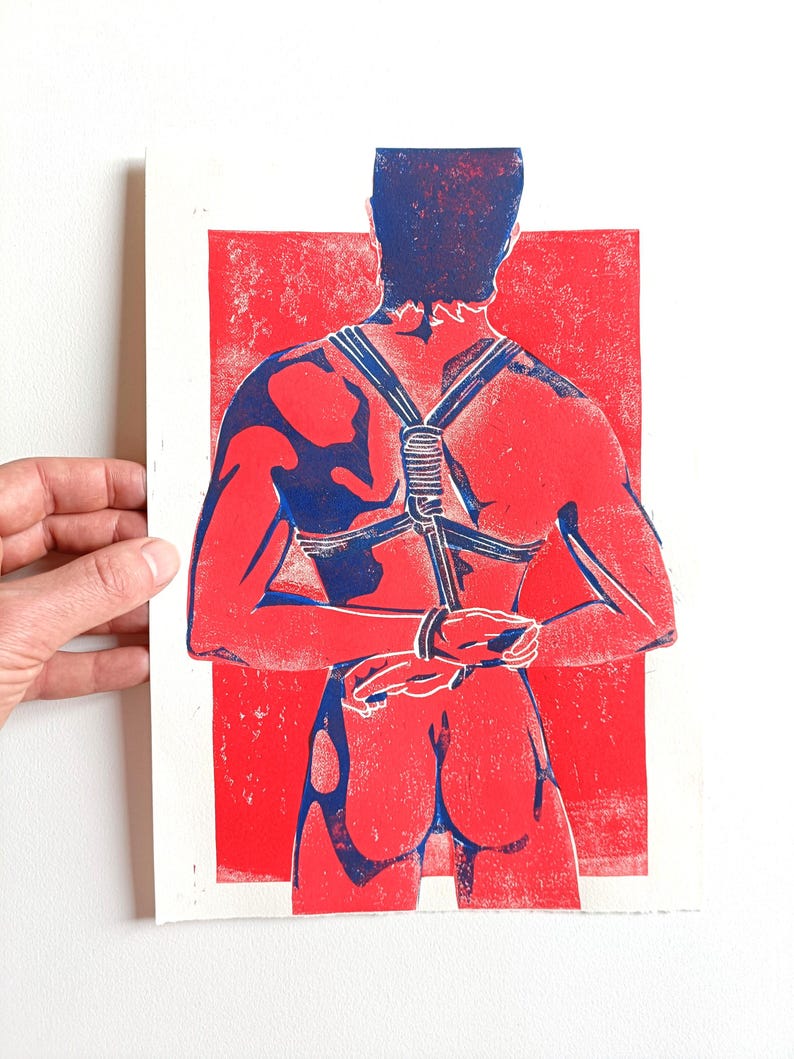 Pu&ograve; includere: Una stampa rossa e blu raffigurante una persona vista da dietro, legata con corde e cinghie. La figura &egrave; posta su uno sfondo rosso, con la corda e le cinghie in blu. La stampa &egrave; su carta bianca.