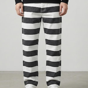 May include: Black and white striped pants. The pants have a straight leg design and are made of a denim material. The pants are paired with white sneakers and a black sweatshirt.