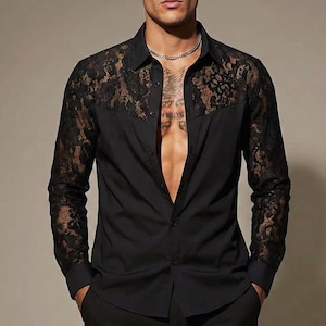 May include: Black long-sleeve shirt with lace detailing on the shoulders and sleeves. The shirt has a classic collar and button-down front. The lace is a darker shade than the shirt, creating a contrast. The shirt is made of a smooth, opaque fabric.