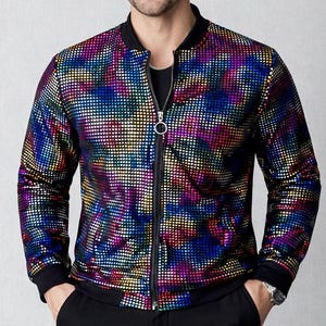 May include: A multi-colored, sequined bomber jacket with a black collar, cuffs, and zipper. The jacket features a vibrant pattern of blue, purple, green, and yellow squares. The model is wearing black pants and sunglasses.